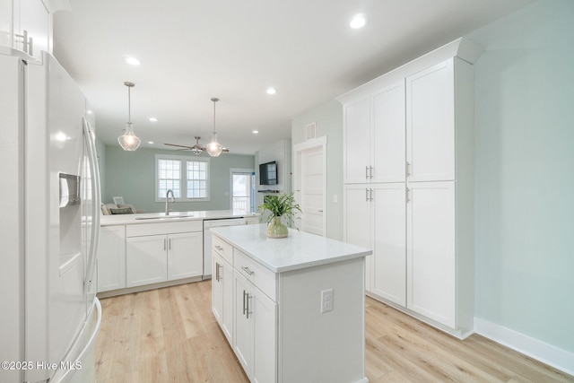 kitchen with white cabinets, a center island, sink, and white fridge with ice dispenser