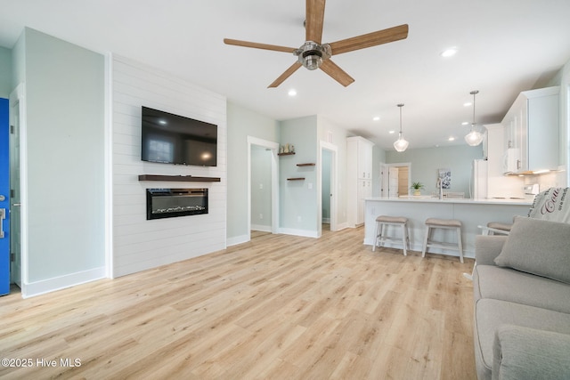 living room with ceiling fan, a fireplace, and light hardwood / wood-style flooring