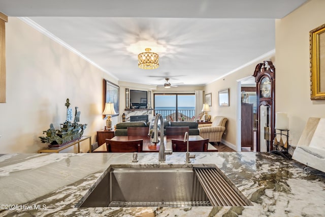 kitchen featuring ceiling fan with notable chandelier, ornamental molding, and sink