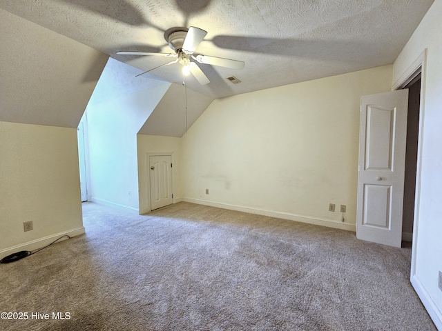 additional living space with lofted ceiling, light colored carpet, a textured ceiling, and ceiling fan