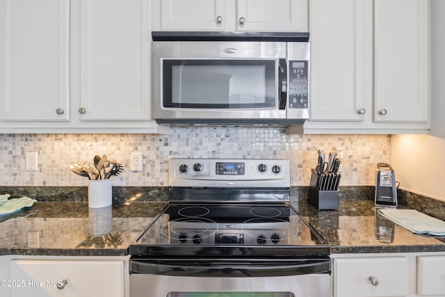 kitchen featuring white cabinetry, stainless steel appliances, and dark stone counters