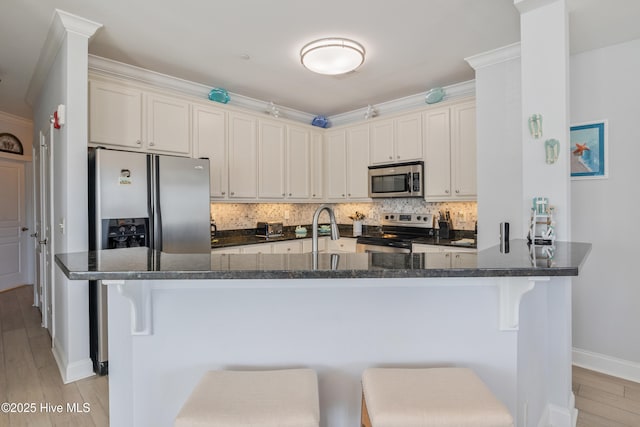 kitchen with tasteful backsplash, appliances with stainless steel finishes, and a breakfast bar