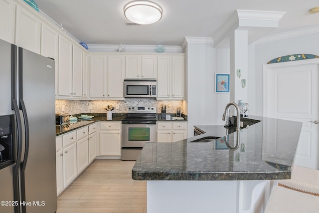 kitchen with crown molding, dark stone countertops, appliances with stainless steel finishes, white cabinets, and backsplash