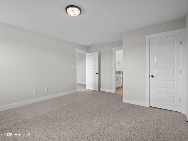 unfurnished bedroom featuring ensuite bath, baseboards, and carpet floors