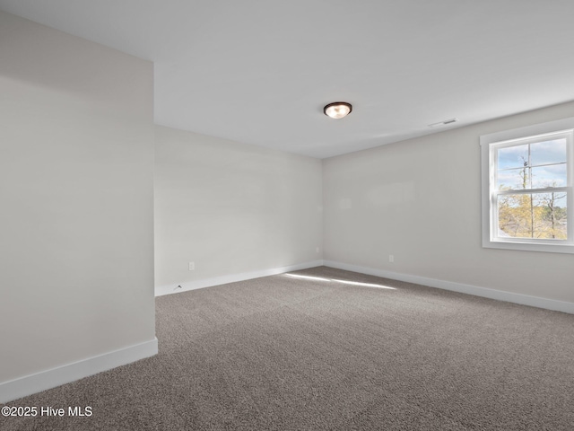 empty room featuring visible vents, baseboards, and carpet