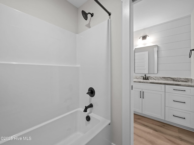 bathroom with washtub / shower combination, vanity, and wood finished floors