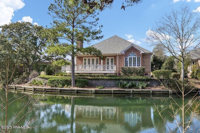 rear view of property with french doors and a water view