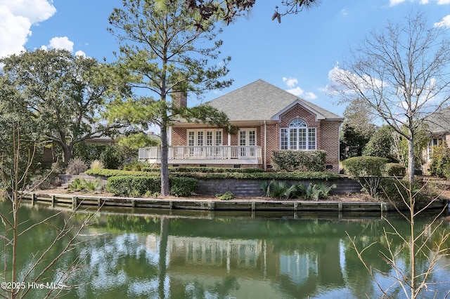 rear view of property featuring a water view and french doors