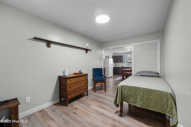 bedroom with light hardwood / wood-style flooring and white fridge