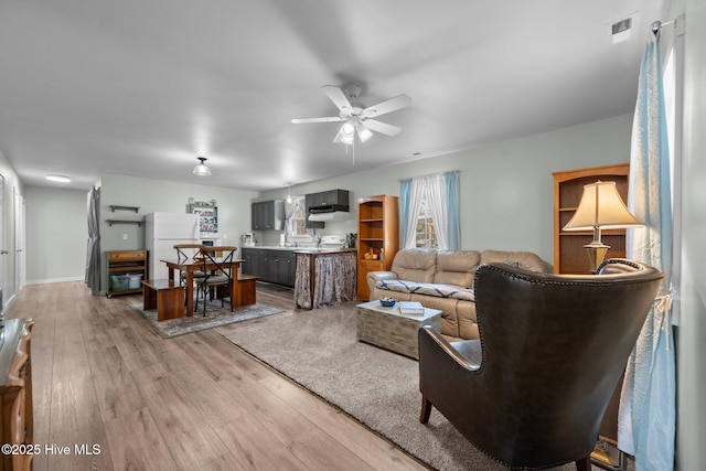 living room with light hardwood / wood-style flooring and ceiling fan