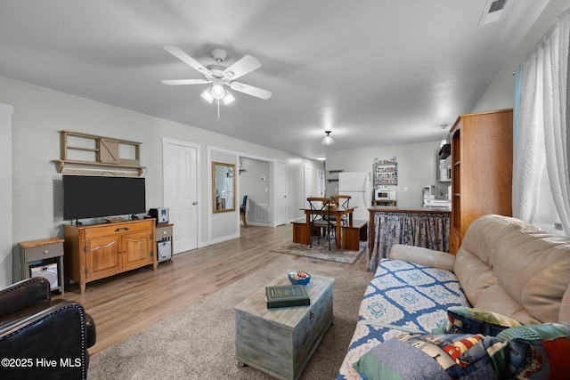 living room with ceiling fan and light hardwood / wood-style flooring