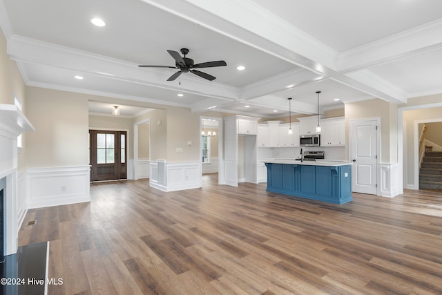 kitchen with light hardwood / wood-style flooring, blue cabinetry, a kitchen island with sink, white cabinets, and decorative light fixtures