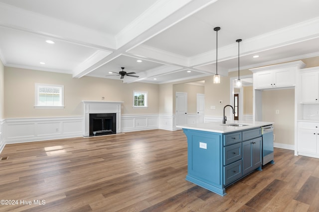 kitchen with a wealth of natural light, an island with sink, white cabinets, blue cabinets, and decorative light fixtures