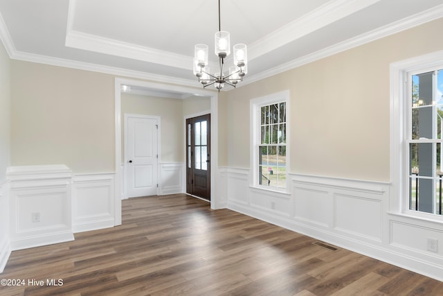 unfurnished dining area featuring a notable chandelier, crown molding, dark wood-type flooring, and a raised ceiling