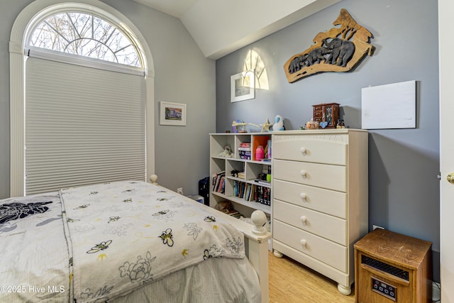 bedroom with vaulted ceiling and light wood-type flooring