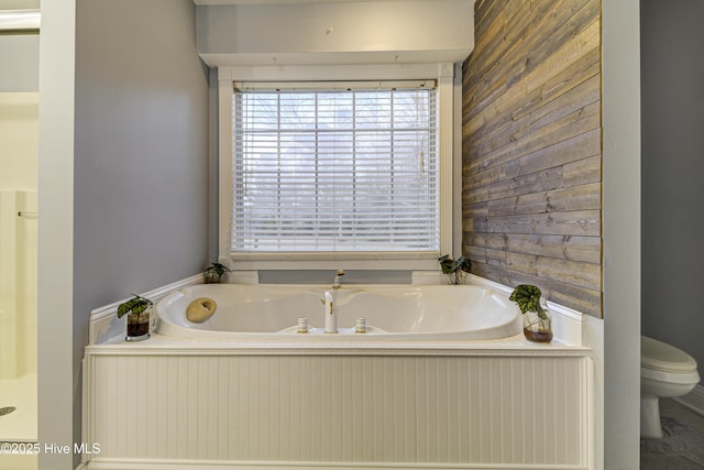 bathroom featuring toilet, wood walls, and a tub to relax in