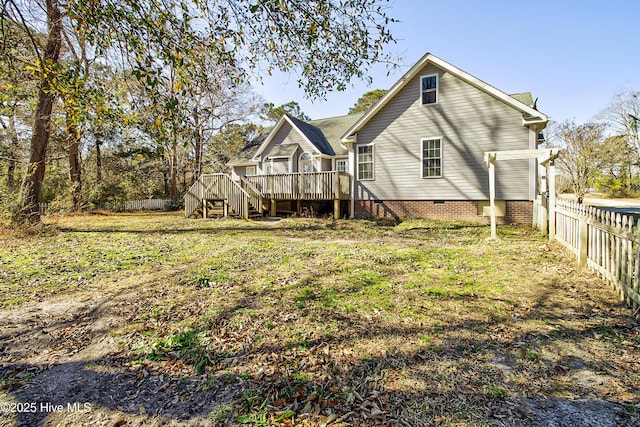 rear view of property featuring a deck and a lawn