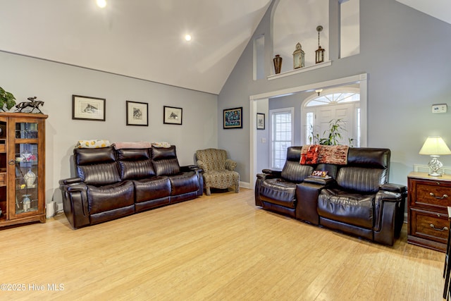 living room with high vaulted ceiling and light wood-type flooring