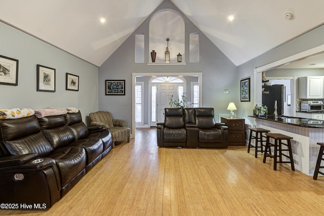 living room featuring high vaulted ceiling and light wood-type flooring