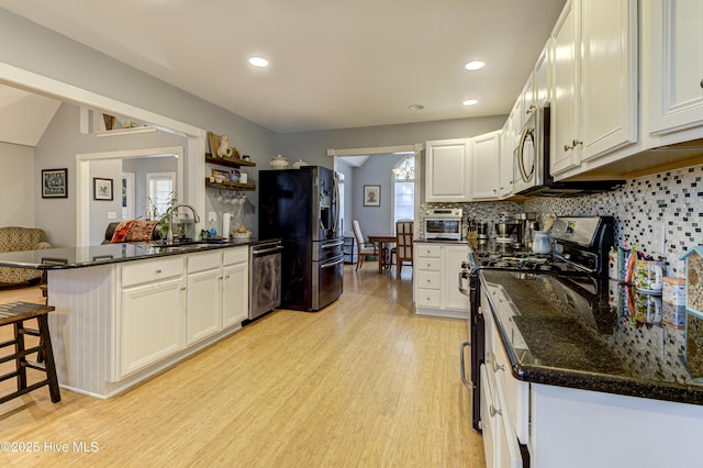 kitchen featuring sink, a breakfast bar area, white cabinetry, appliances with stainless steel finishes, and light hardwood / wood-style floors