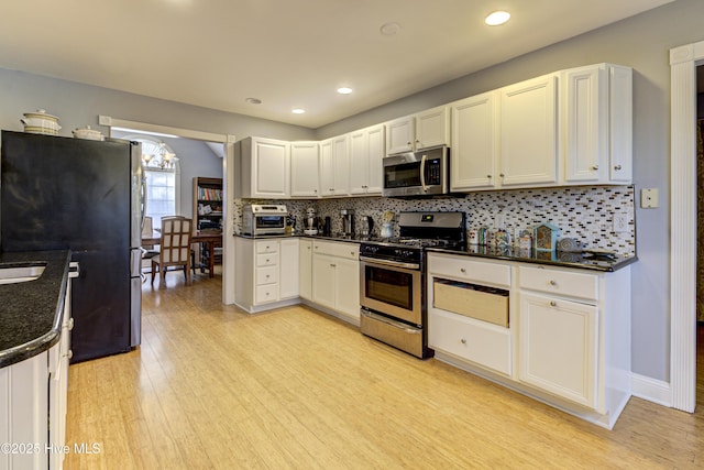 kitchen with white cabinetry, tasteful backsplash, appliances with stainless steel finishes, and light hardwood / wood-style flooring