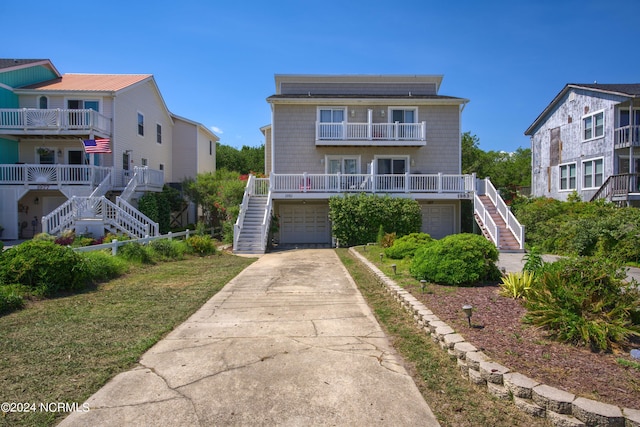 view of front of home featuring concrete driveway, a balcony, stairway, and an attached garage