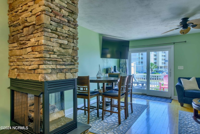 1981 New River Inlet Rd, North Topsail Beach, NC 28460 - dining space with a fireplace, wood-type flooring, a textured ceiling, and ceiling fan