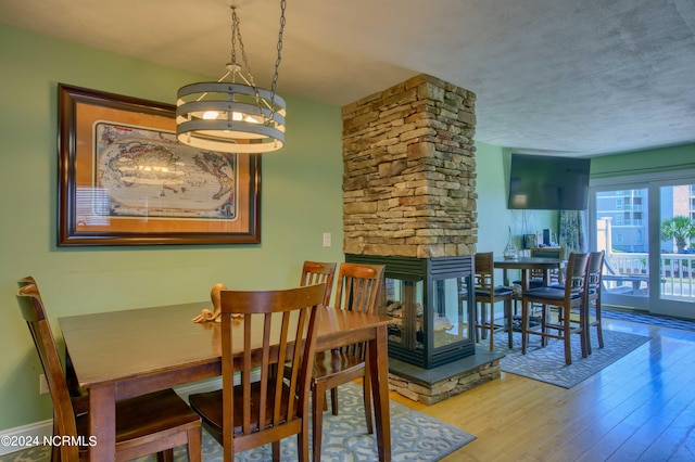 1981 New River Inlet Rd, North Topsail Beach, NC 28460 - dining room with a chandelier, a fireplace, wood finished floors, and a textured ceiling