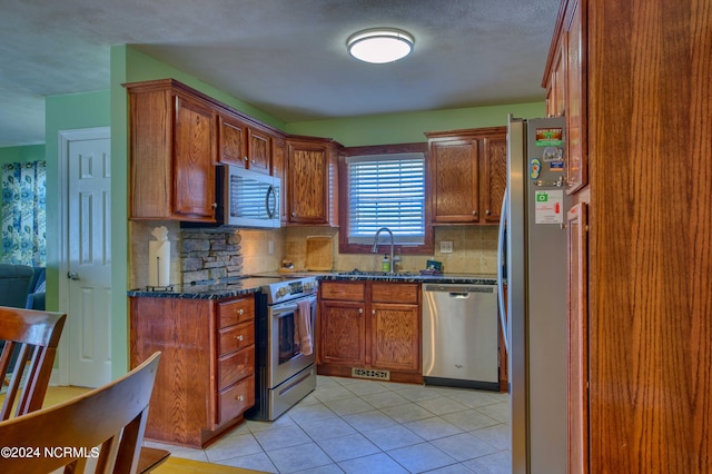 1981 New River Inlet Rd, North Topsail Beach, NC 28460 - kitchen featuring appliances with stainless steel finishes, decorative backsplash, light tile patterned floors, and brown cabinets