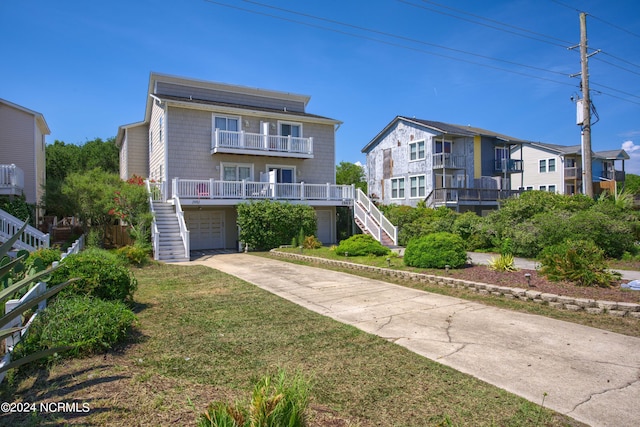 view of front of home with solar panels, concrete driveway, stairway, an attached garage, and a balcony