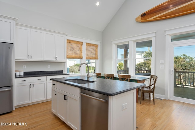 kitchen featuring appliances with stainless steel finishes, white cabinetry, an island with sink, sink, and lofted ceiling