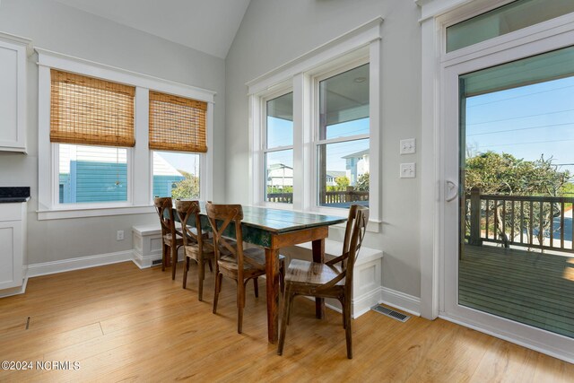 dining room featuring vaulted ceiling and light hardwood / wood-style floors