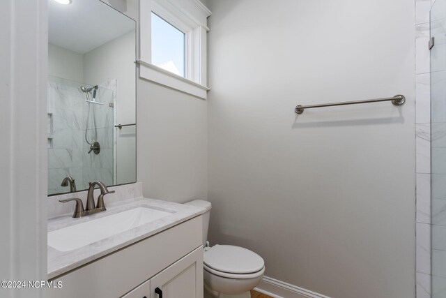 bathroom with vanity, toilet, and a tile shower