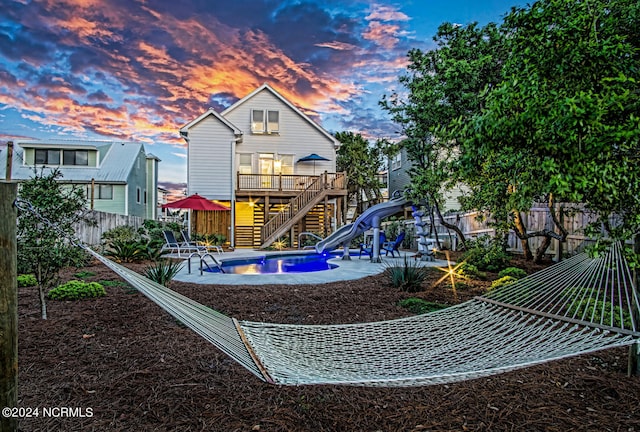 playground at dusk featuring a fenced in pool and a patio