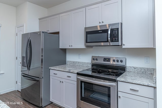 kitchen with light stone countertops, stainless steel appliances, and dark hardwood / wood-style floors