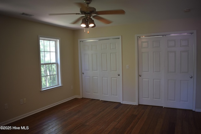 7304 E Oak Island Dr, Oak Island, NC 28465 - unfurnished bedroom with multiple closets, dark wood finished floors, and baseboards