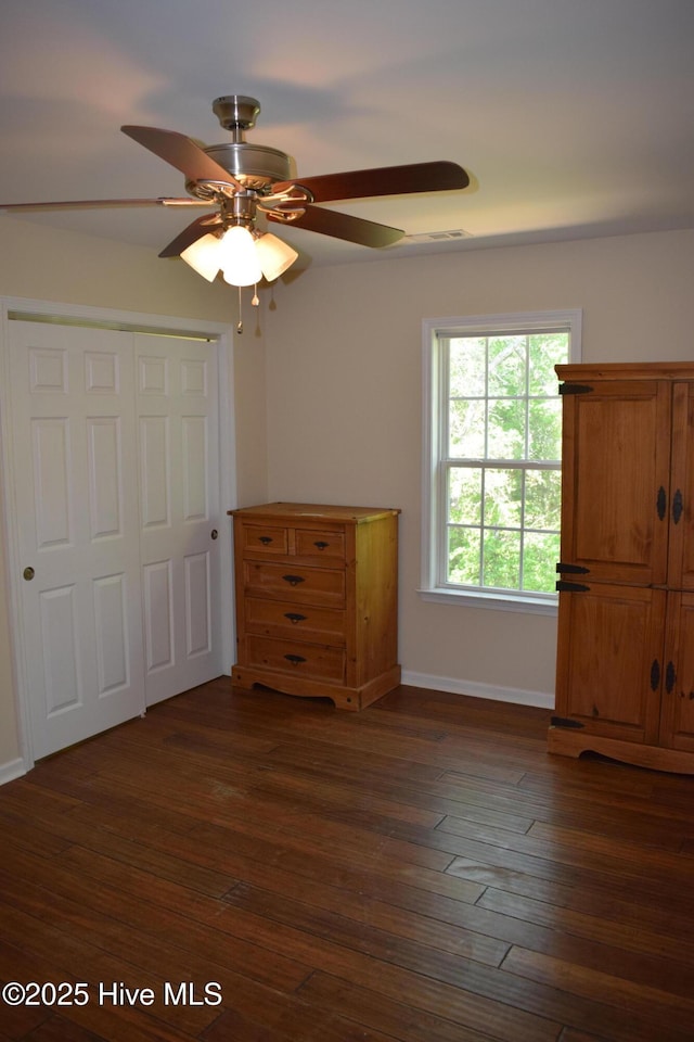 7304 E Oak Island Dr, Oak Island, NC 28465 - unfurnished bedroom with dark wood finished floors, baseboards, a closet, and a ceiling fan