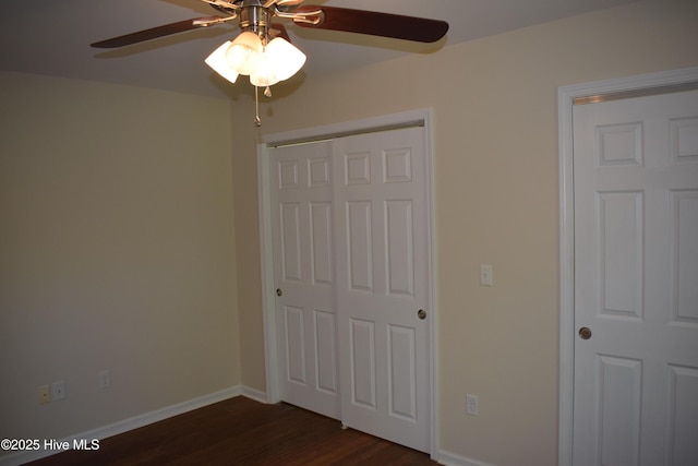 7304 E Oak Island Dr, Oak Island, NC 28465 - unfurnished bedroom featuring dark wood-style flooring, baseboards, a closet, and ceiling fan