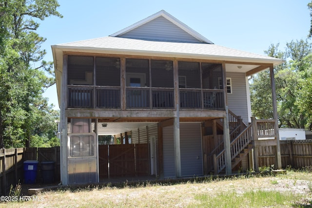 7304 E Oak Island Dr, Oak Island, NC 28465 - rear view of property with roof with shingles, a sunroom, and stairs