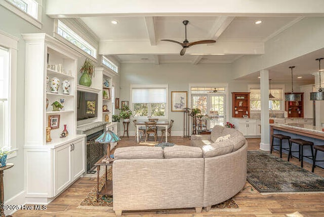 living room with light hardwood / wood-style flooring, ceiling fan, coffered ceiling, beamed ceiling, and ornamental molding