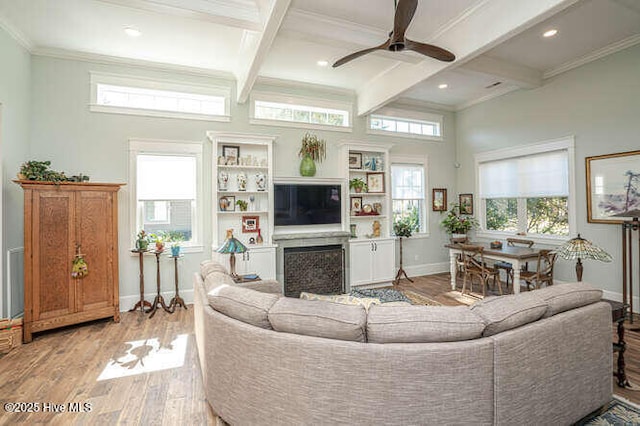 living room featuring ceiling fan, beamed ceiling, light wood-type flooring, and crown molding