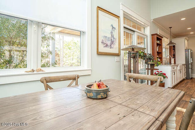 dining area featuring crown molding, wood-type flooring, and sink