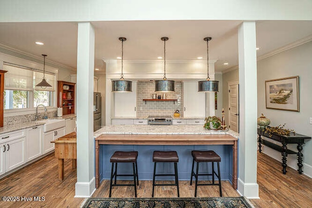 kitchen featuring a breakfast bar area, sink, light stone countertops, and white cabinets