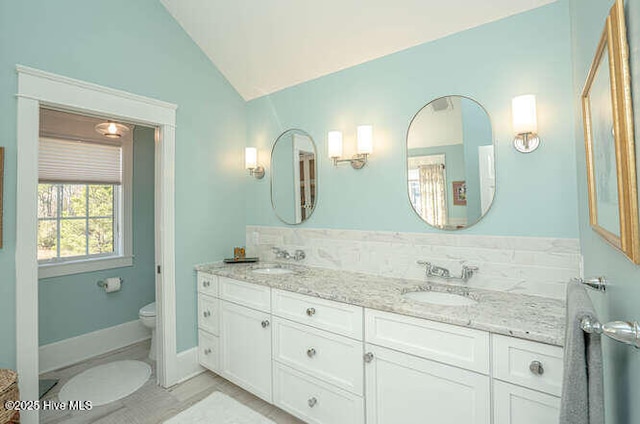 bathroom with lofted ceiling, vanity, and toilet