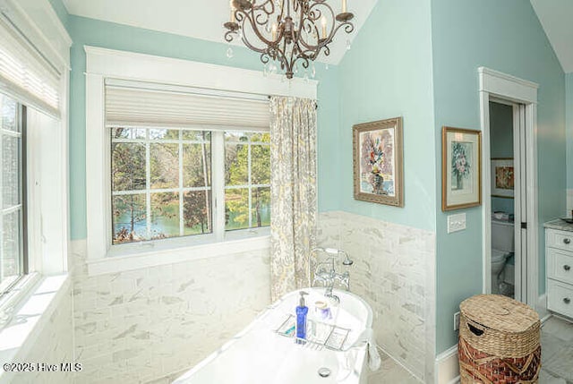 bathroom featuring toilet, vaulted ceiling, an inviting chandelier, and vanity