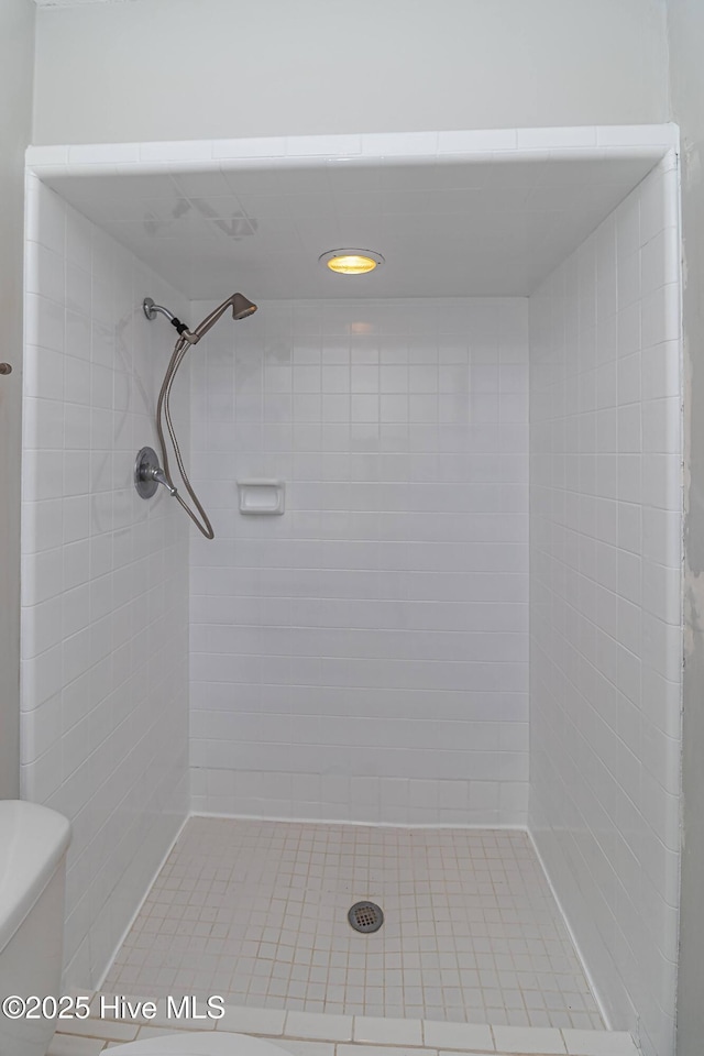 bathroom with a tile shower and toilet