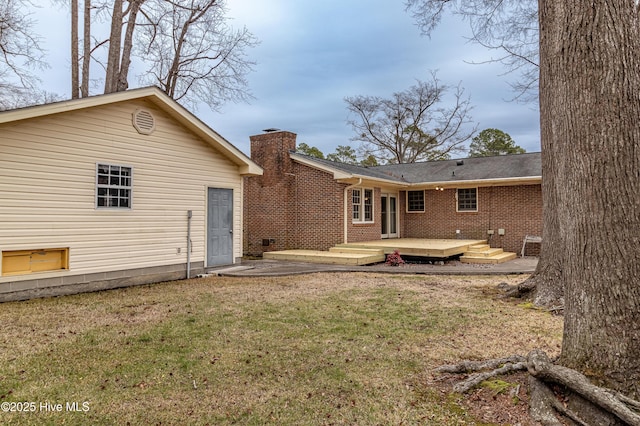 rear view of property featuring a wooden deck and a lawn