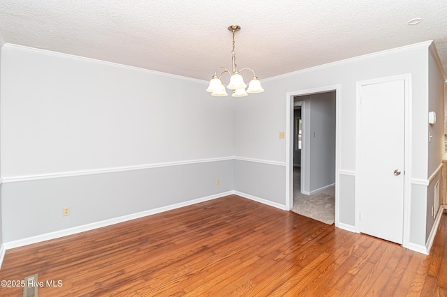 unfurnished room featuring crown molding, hardwood / wood-style floors, a notable chandelier, and a textured ceiling