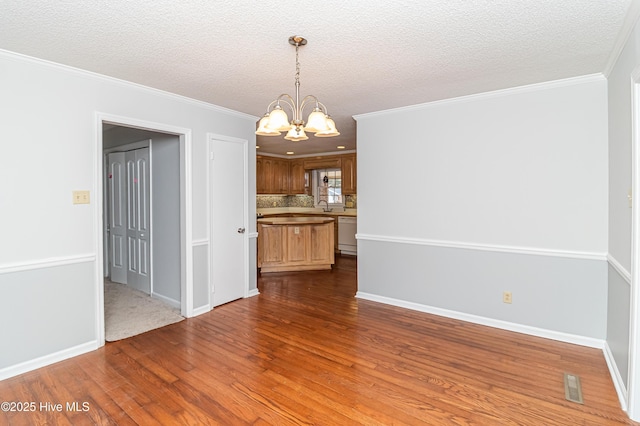 interior space with hardwood / wood-style floors, a notable chandelier, ornamental molding, and a textured ceiling