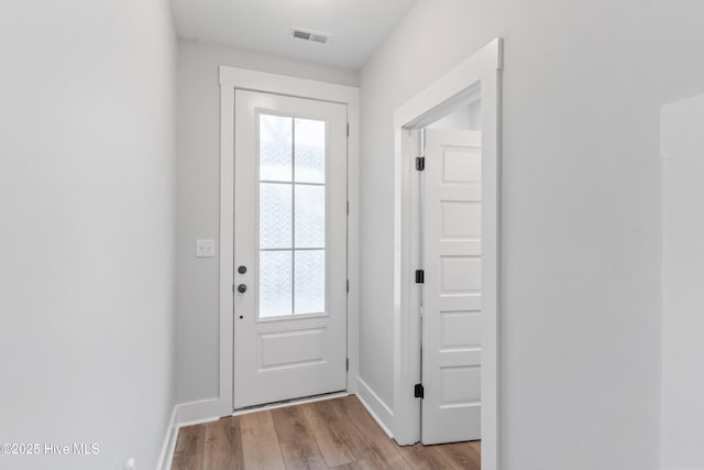 doorway featuring visible vents, plenty of natural light, light wood-style flooring, and baseboards